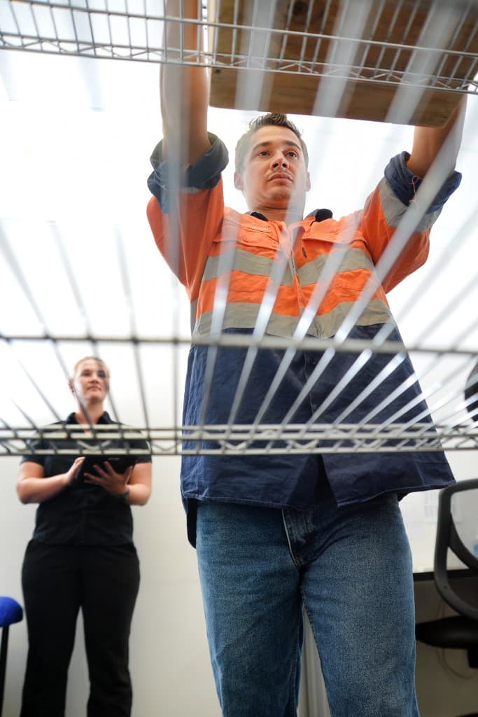 High-vis worker performing a functional capacity lift test during a KINNECT pre-employment functional assessment