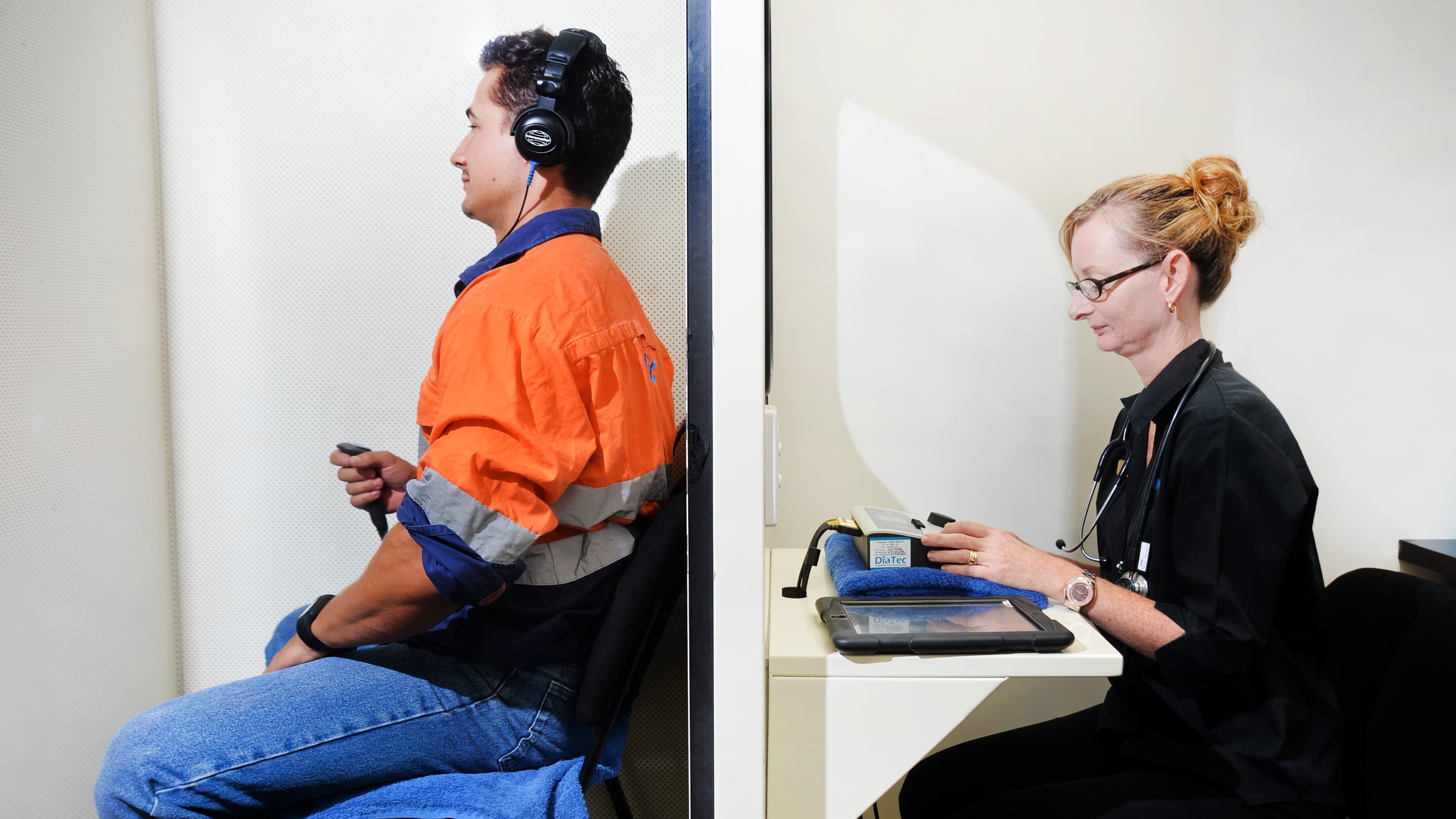 KINNECT audiologist conducting an audiometric hearing test on a high-vis worker inside an onsite soundproof booth