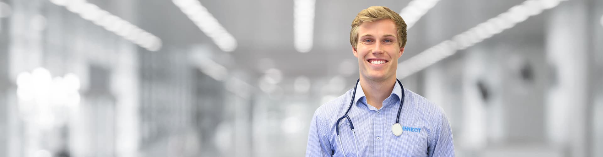 A KINNECT occupational physician in branded shirt smiling during a workplace medical consultation