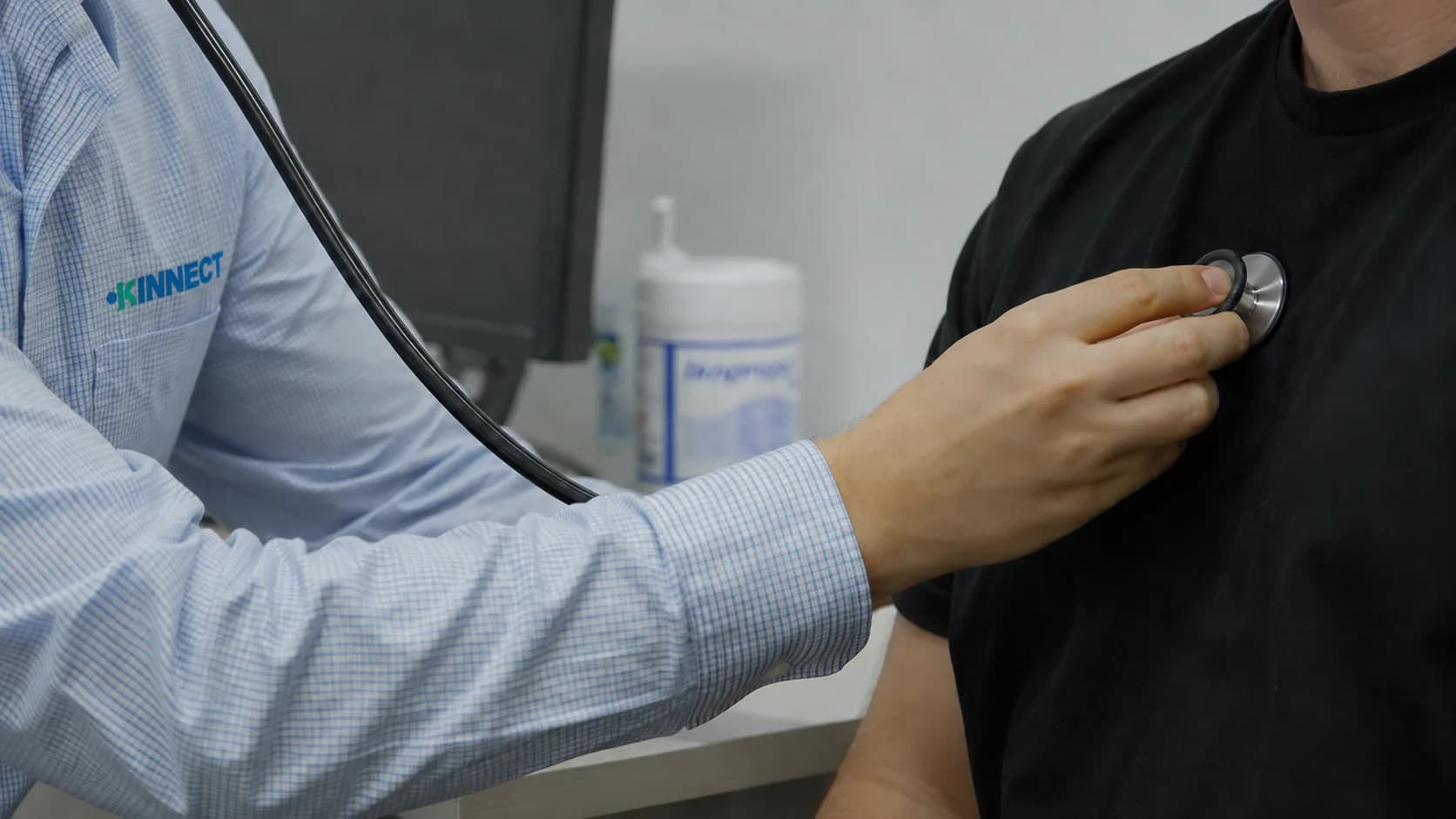 KINNECT clinician listening to a worker's heart sounds with a stethoscope during a clinical examination