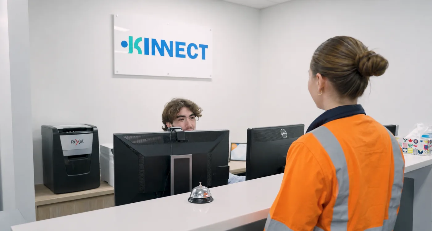 A worker speaking with a receptionist at a KINNECT office reception desk