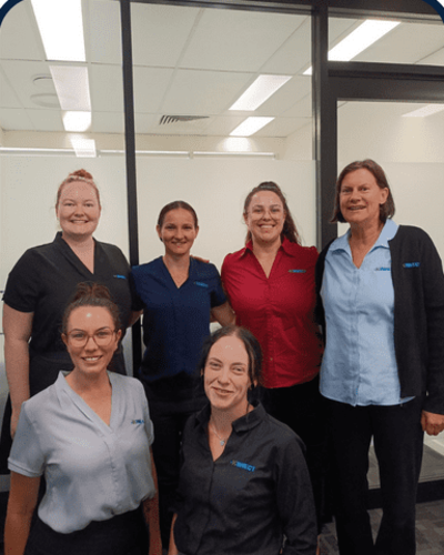 KINNECT Cairns team members standing together in the office, smiling in branded uniforms.