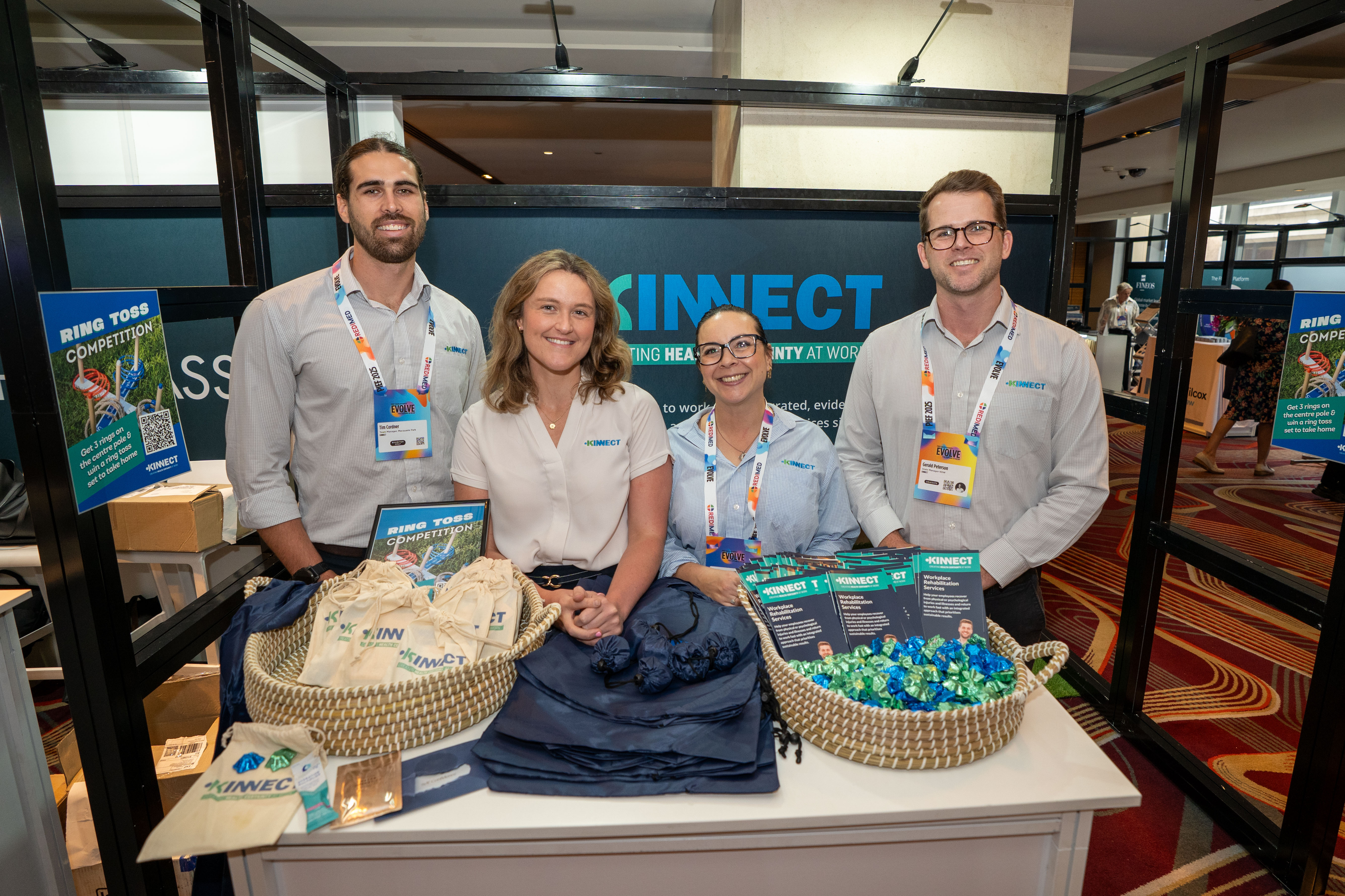 Four KINNECT team members behind a branded KINNECT stand with ring-toss baskets at the PIEF Conference