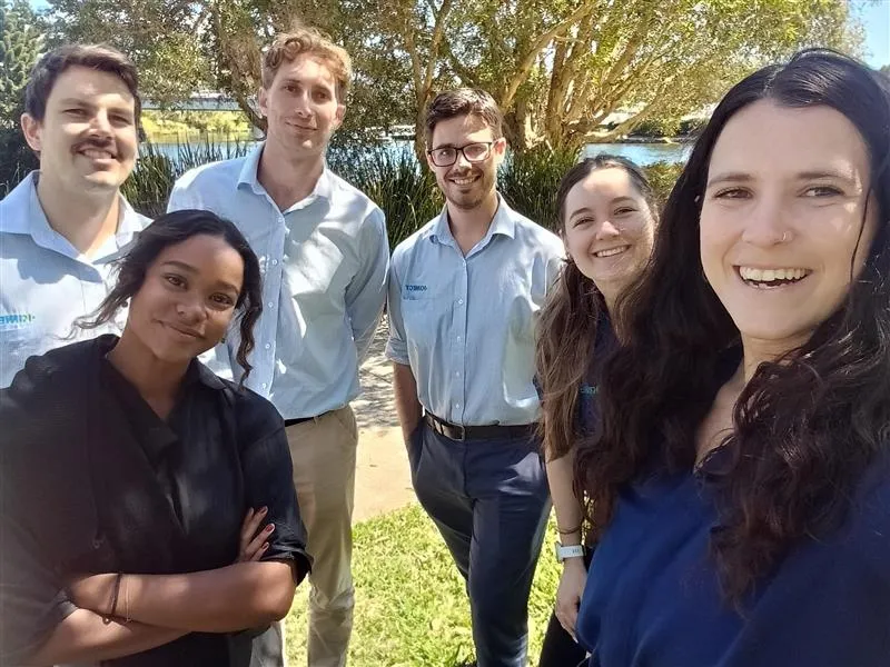 A small KINNECT team posed together outdoors by a river